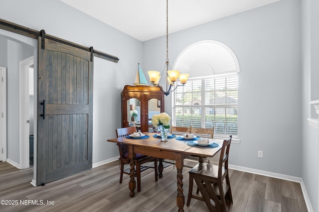 dining room featuring baseboards, a barn door, a chandelier, and wood finished floors