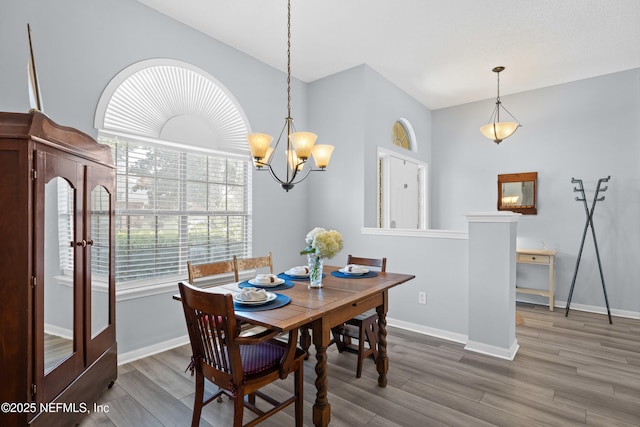 dining space with an inviting chandelier, baseboards, and wood finished floors