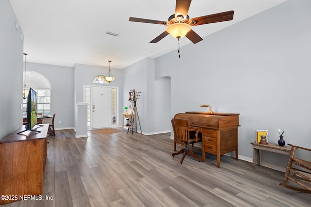 office space featuring dark wood-style floors, ceiling fan with notable chandelier, visible vents, and baseboards