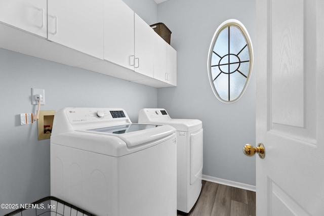 washroom featuring dark wood-type flooring, washing machine and dryer, cabinet space, and baseboards