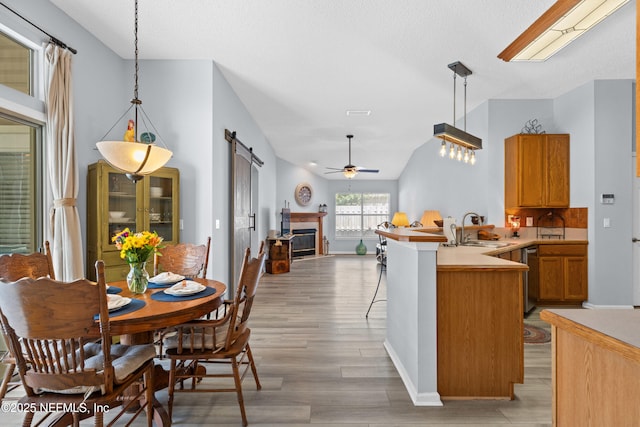 kitchen featuring a barn door, lofted ceiling, a peninsula, light wood-style floors, and a sink