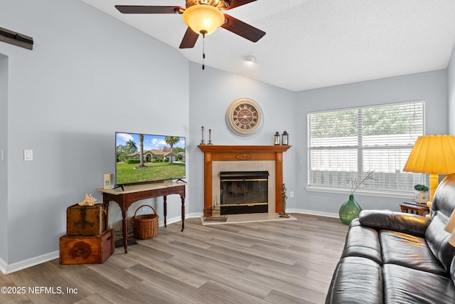 living area with vaulted ceiling, ceiling fan, wood finished floors, and a high end fireplace