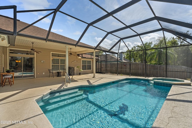 view of pool with glass enclosure, a pool with connected hot tub, fence, and a patio