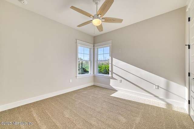 carpeted spare room featuring baseboards and ceiling fan