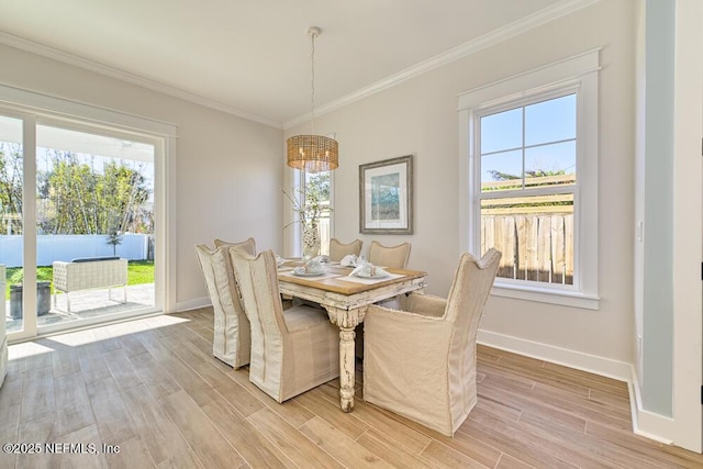 dining room featuring a wealth of natural light, baseboards, crown molding, and light wood-style floors