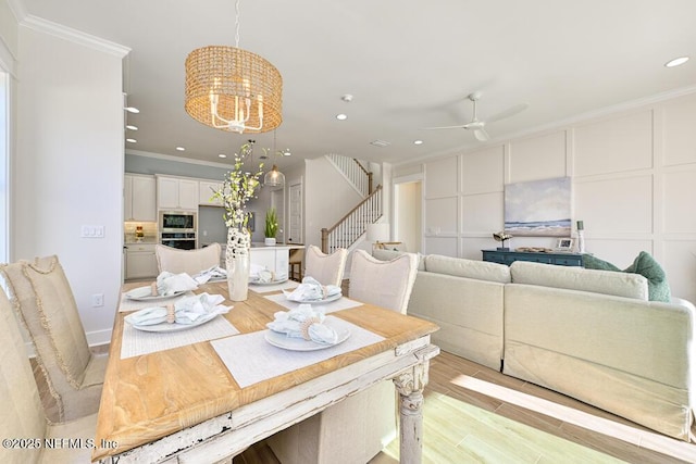 dining area with ornamental molding, recessed lighting, stairway, light wood-style floors, and a decorative wall