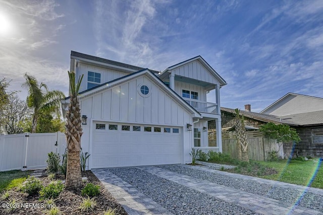 view of front facade featuring decorative driveway, a balcony, board and batten siding, and fence