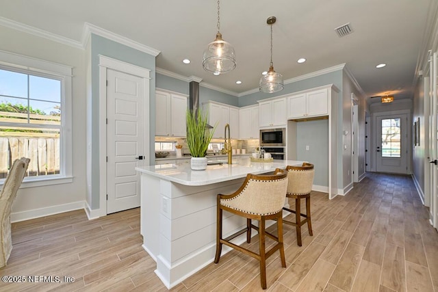 kitchen featuring light wood-type flooring, visible vents, tasteful backsplash, light countertops, and built in microwave