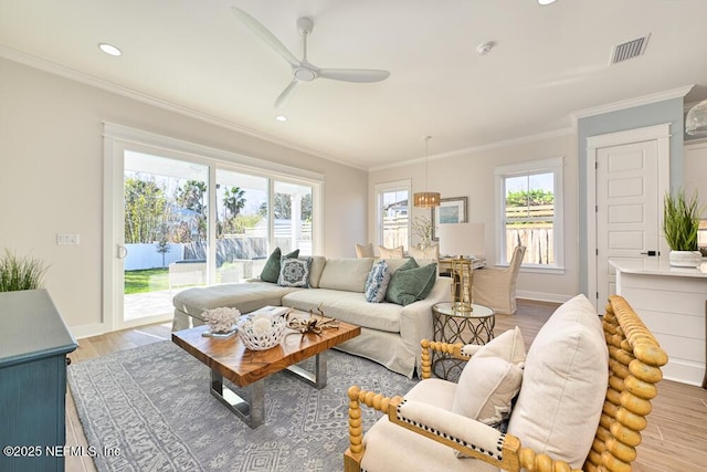 living room featuring a wealth of natural light, light wood-style flooring, and crown molding