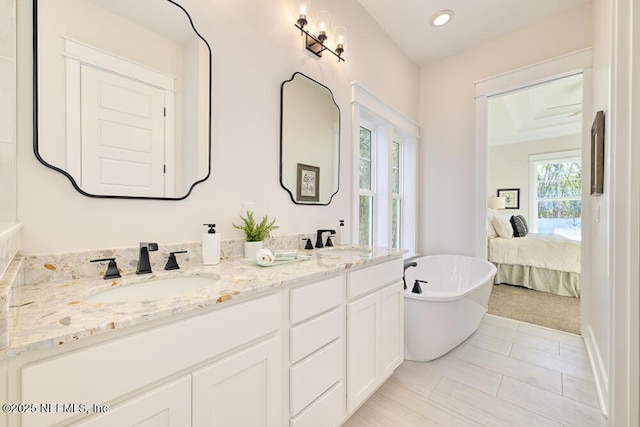 bathroom featuring a sink, a freestanding bath, recessed lighting, and double vanity