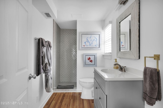 full bathroom with visible vents, toilet, a stall shower, wood finished floors, and vanity