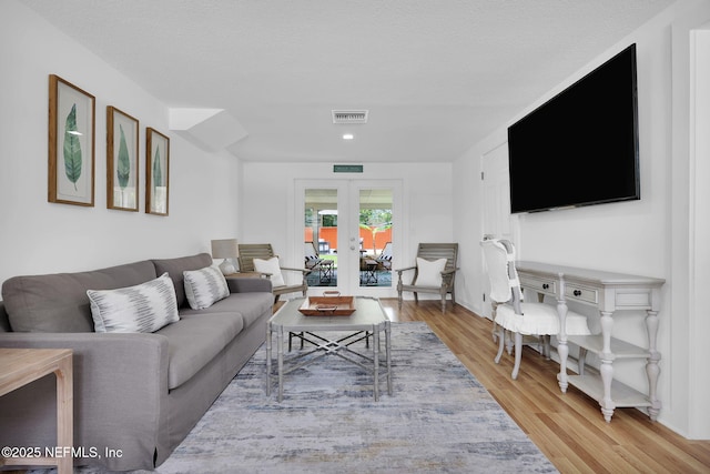 living room featuring visible vents, french doors, and light wood-type flooring