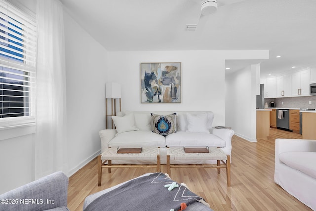 living area with recessed lighting, light wood-type flooring, and baseboards