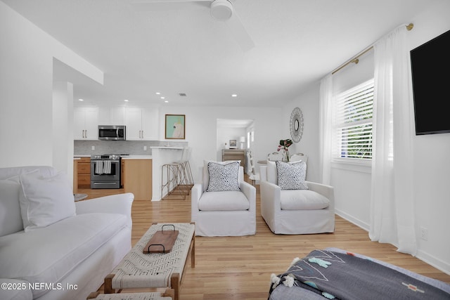 living room with baseboards, recessed lighting, light wood-type flooring, and ceiling fan