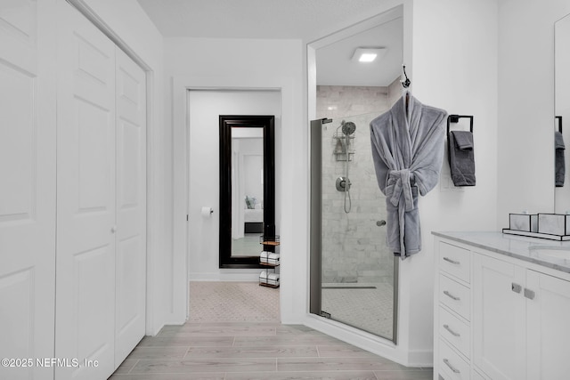 full bath with vanity, a shower stall, wood finished floors, and baseboards