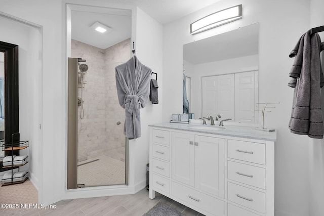 full bath with vanity, wood finished floors, and a stall shower