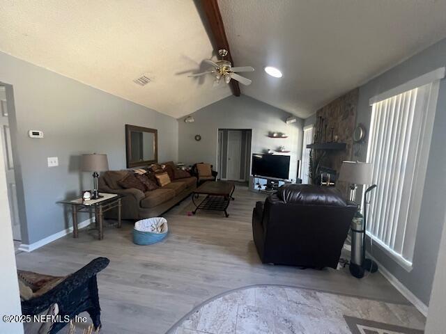 living room with vaulted ceiling with beams, wood finished floors, a ceiling fan, visible vents, and baseboards