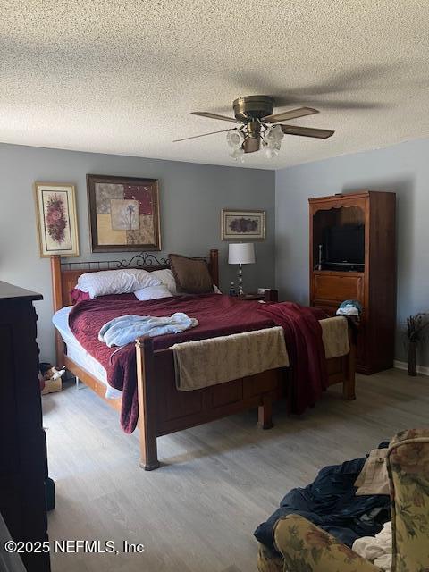 bedroom with ceiling fan, light wood-style flooring, and a textured ceiling