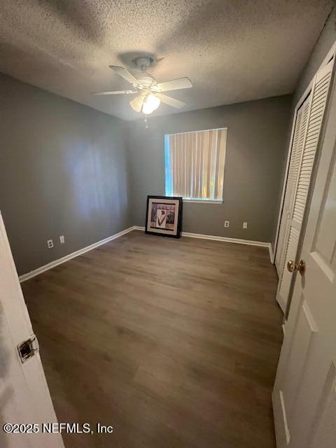 unfurnished bedroom with baseboards, ceiling fan, wood finished floors, a textured ceiling, and a closet