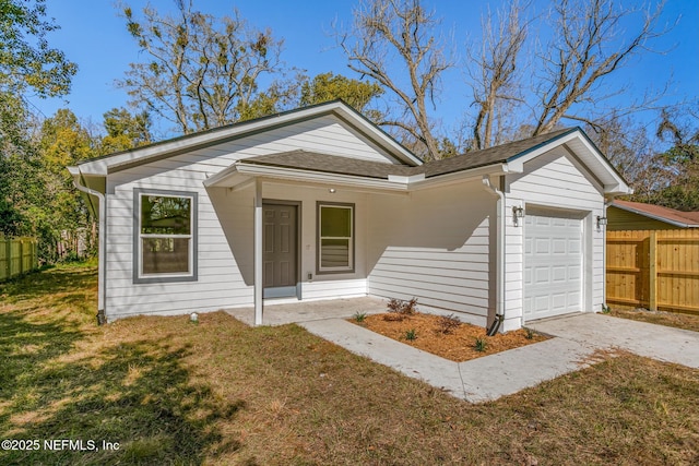 bungalow with a garage, a shingled roof, concrete driveway, fence, and a front lawn