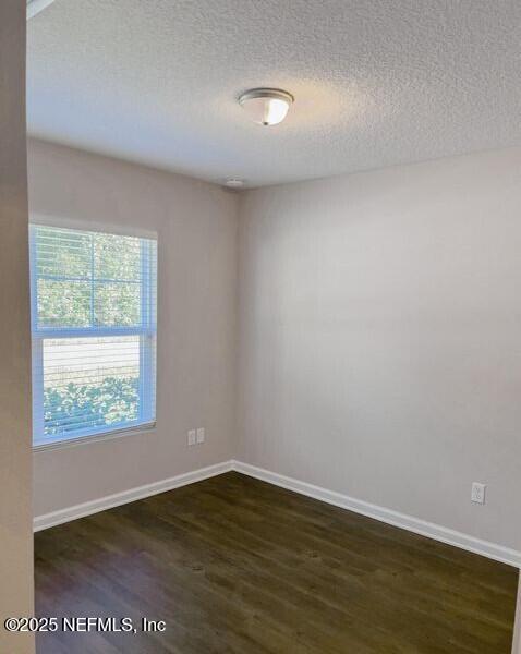 empty room with dark wood-style floors, baseboards, and a textured ceiling