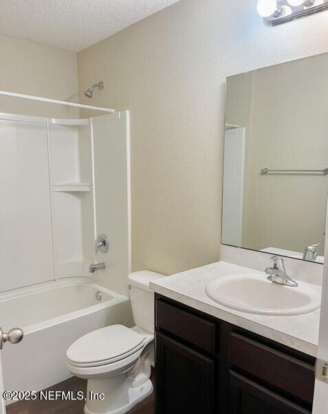 bathroom featuring shower / washtub combination, toilet, a textured ceiling, and vanity