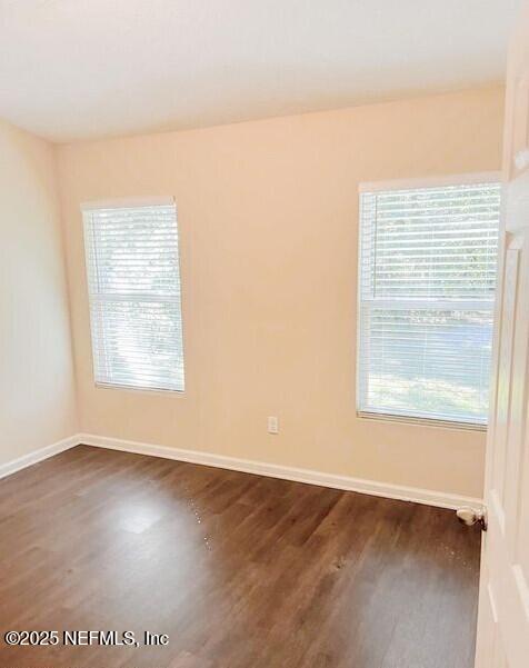 spare room featuring baseboards and dark wood-style flooring