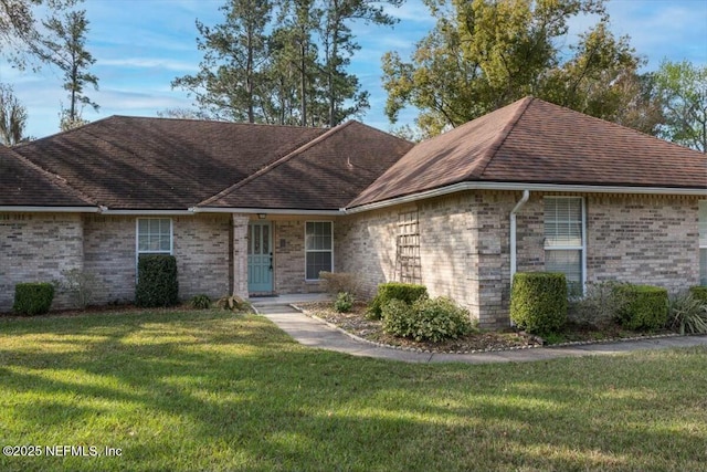 ranch-style house with brick siding, a front yard, and a shingled roof