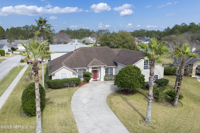 ranch-style house with a shingled roof, a front lawn, concrete driveway, and stucco siding