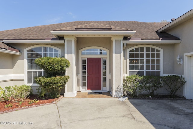 property entrance featuring roof with shingles and stucco siding