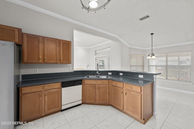 kitchen featuring white dishwasher, a sink, visible vents, freestanding refrigerator, and dark countertops