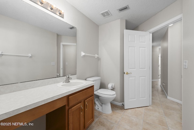 bathroom featuring a textured ceiling, toilet, vanity, visible vents, and tile patterned floors