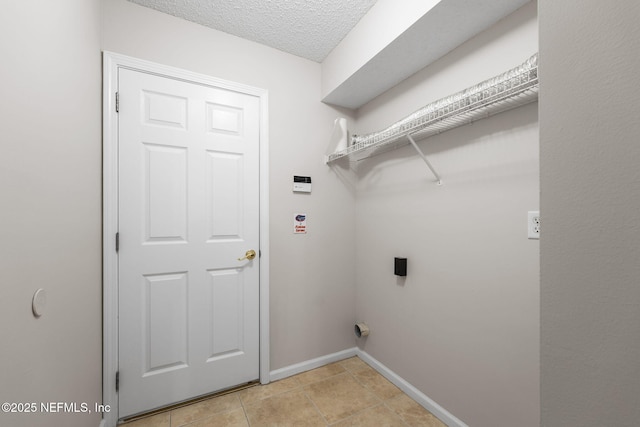 clothes washing area featuring hookup for an electric dryer, light tile patterned flooring, a textured ceiling, laundry area, and baseboards