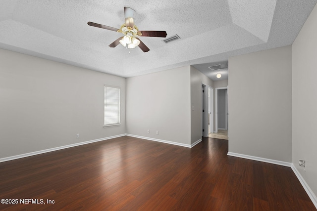 empty room with visible vents, a textured ceiling, baseboards, and wood finished floors