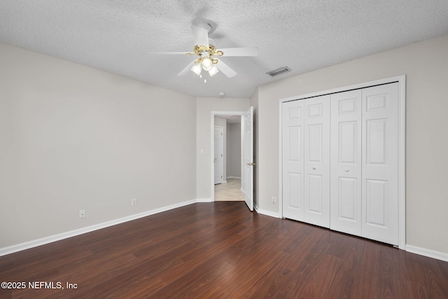 unfurnished bedroom featuring visible vents, a textured ceiling, baseboards, and wood finished floors