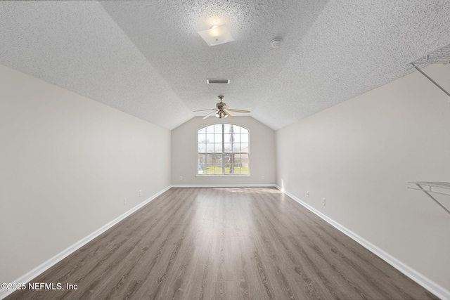 unfurnished room featuring lofted ceiling, visible vents, baseboards, and wood finished floors