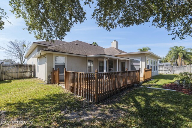 rear view of house featuring a shingled roof, a fenced backyard, a chimney, a yard, and stucco siding