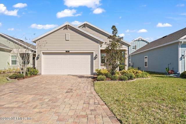 view of front of home with an attached garage, decorative driveway, and a front yard