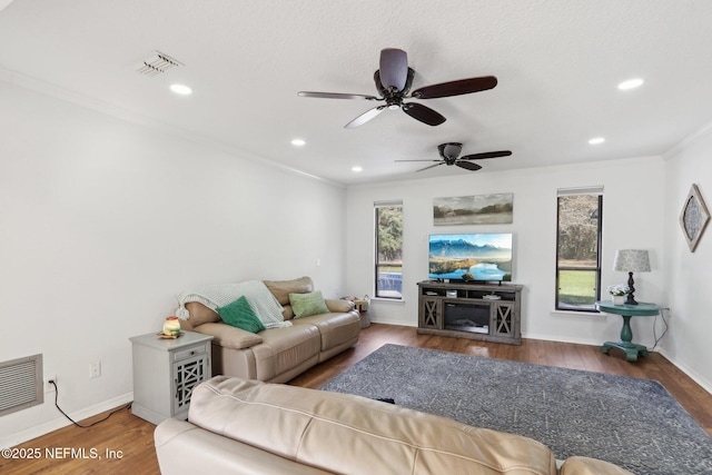 living area featuring ornamental molding, visible vents, baseboards, and wood finished floors