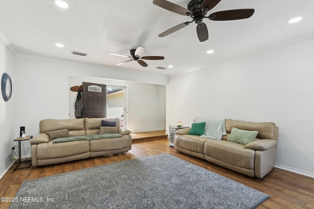 living area with baseboards, visible vents, wood finished floors, and ornamental molding