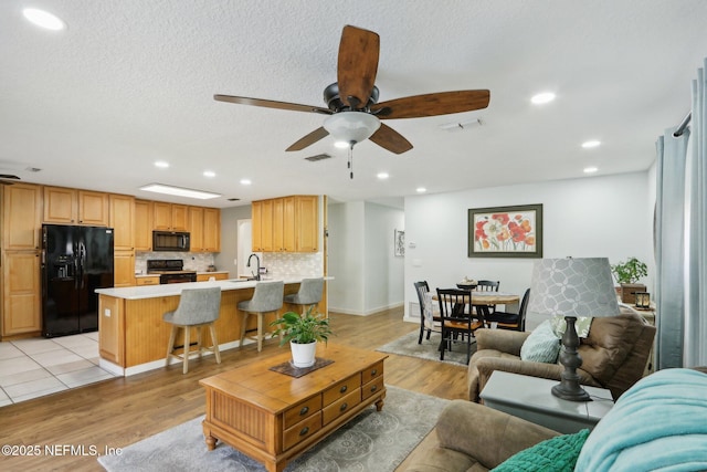 living room featuring light wood-type flooring, visible vents, and recessed lighting