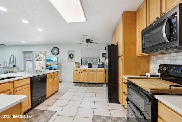 kitchen with black appliances, backsplash, a sink, and light countertops