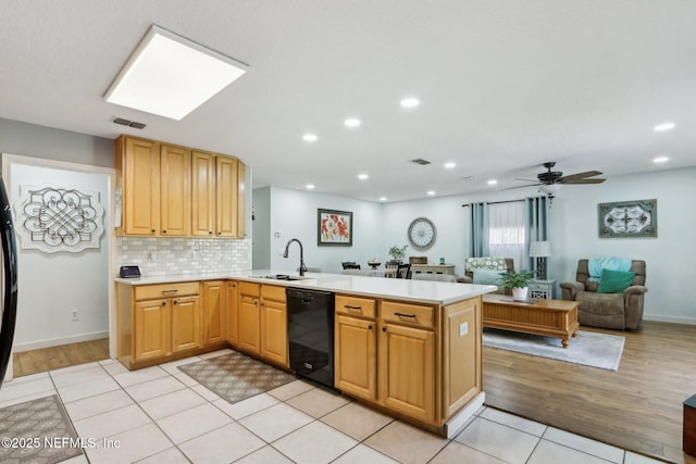 kitchen featuring black dishwasher, light countertops, a sink, and a peninsula