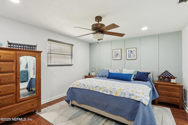 bedroom featuring visible vents, wood finished floors, a ceiling fan, and a decorative wall