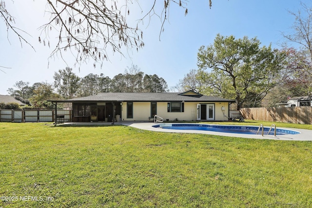 rear view of property with a sunroom, a yard, a fenced backyard, and a fenced in pool