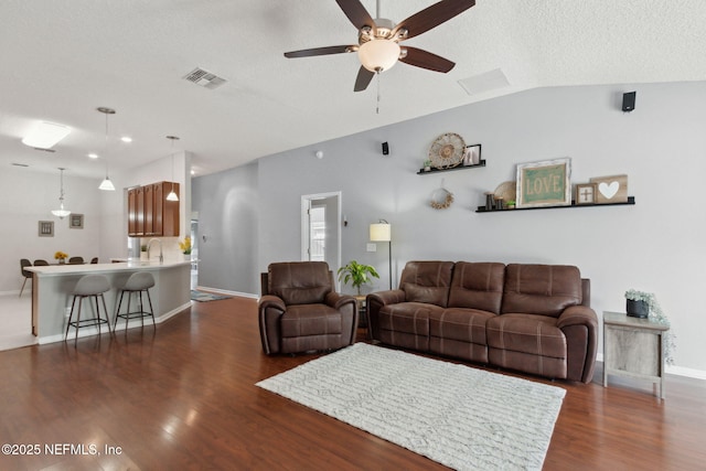 living room with dark wood-style floors, visible vents, vaulted ceiling, and a textured ceiling