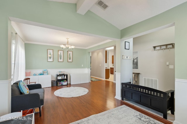 living area featuring vaulted ceiling with beams, wood finished floors, visible vents, and a notable chandelier