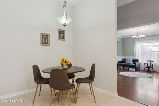 dining room featuring crown molding, a notable chandelier, baseboards, and wood finished floors