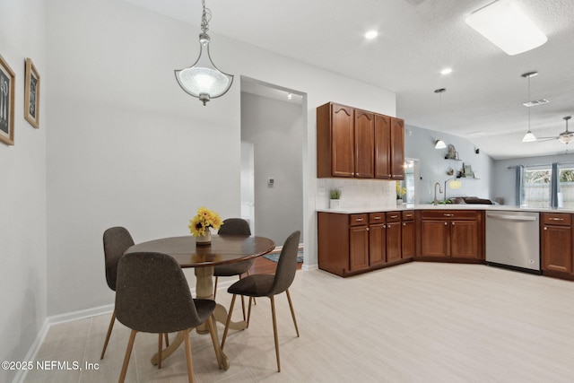 kitchen with pendant lighting, light countertops, visible vents, decorative backsplash, and dishwasher