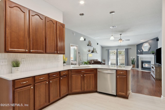 kitchen featuring open floor plan, a peninsula, stainless steel dishwasher, and a sink